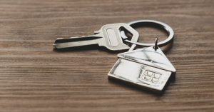 image of house key chain on wood background for article Difference Between Joint Tenancy and Community Property