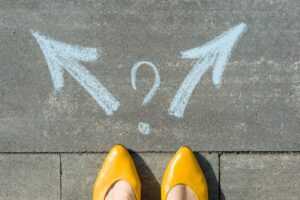 female feet in yellow shoes pointing toward quesion mark and arrows going towards opposite direction for article by kelley way titled copyright vs. trademark what's the difference