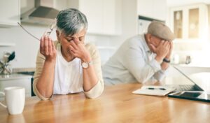 frustrated senior couple at table, holding their heads in their hands is the featured image for the article by kelley way titled