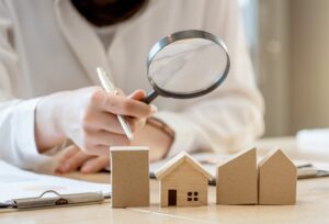 person looking through a magnifying lens at a group of wooden block toy homes as featured image for article by kelley way titles estate planning myths