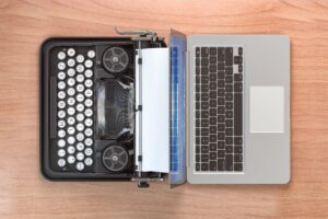 a old fashioned type writer next to a modern laptop is the featured image for the blog article by kelley way titled what can a writer do with AI