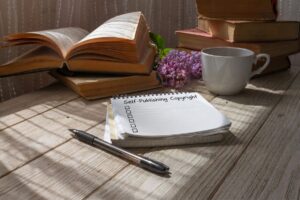 Open notebook with checklist titled self publishing copyright on desk with streaming sunlight with a pen, a cup of tea and books is the featured image for the blog article by kelley way titled Self-Publishing Copyright Checklist: What to Do After You Publish
