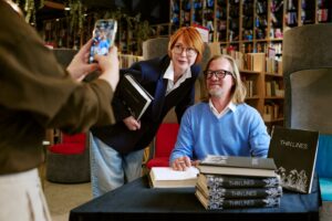 Author Signing Books While Being Photographed for blog article by kelley way titled Brand Protection 101: A Checklist for Self-Published Authors