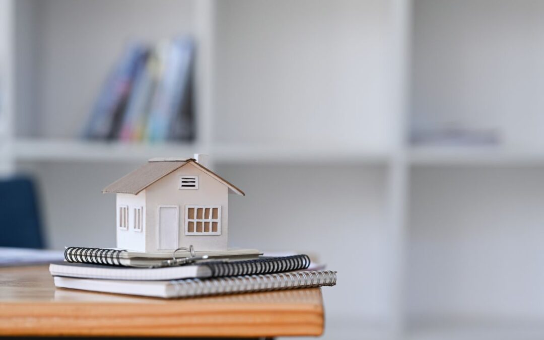 small house model on top of a stack of books and papers as the featured image for blog article by Kelley Way titled Tips for Preparing Your Estate and Literary Estate