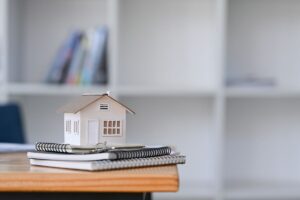 small house model on top of a stack of books and papers as the featured image for blog article by Kelley Way titled Tips for Preparing Your Estate and Literary Estate